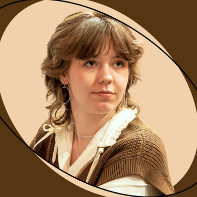 A white person with brown hair, a white collared shirt, and a brown vest. Photo credit: Jenn Udoni.