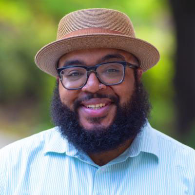 A Black male wearing a gold porkpie hat.