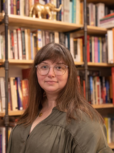 A white woman with long brown and grey hair, wearing glasses with clear acrylic frames.