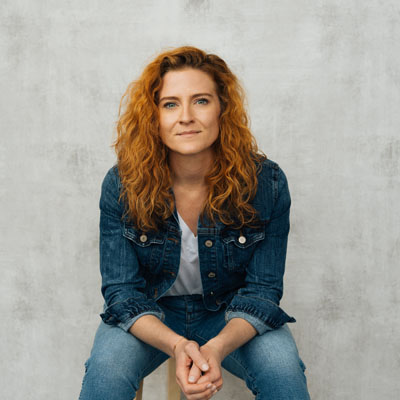 A white woman with long, curly red-ish hair. Photo credit: Will Crooks 