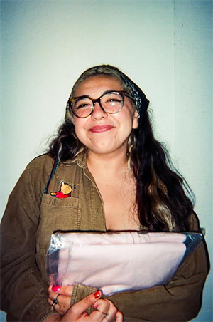A smiling young woman with long dark hair and glasses.