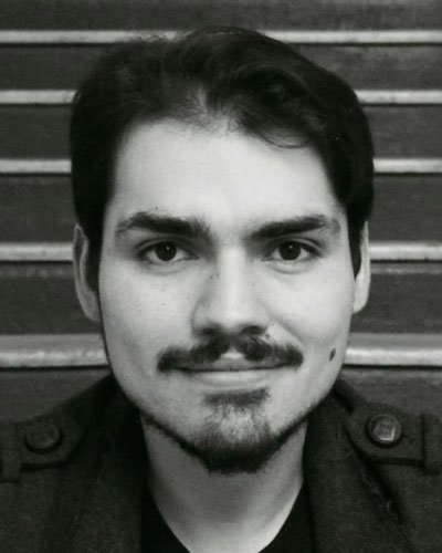 Mexican man with a t-shirt, black jacket, beard and mustache.