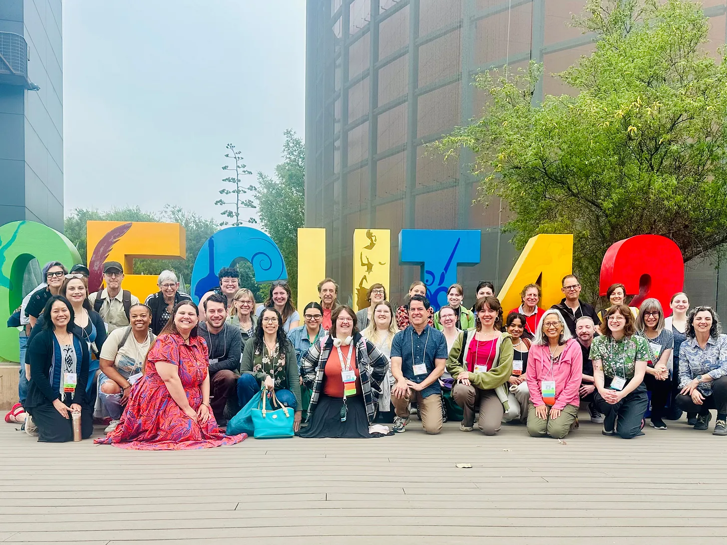 A large group of people pose together outdoors in front of colorful oversized letters and numbers spelling CECUT 42. The group is smiling, with some standing and others kneeling, against a backdrop of buildings and trees.