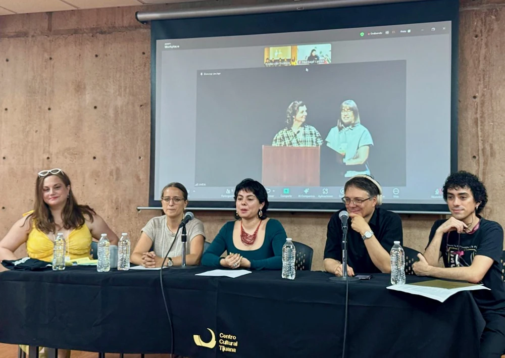 Attendees at a table with microphones, participating in the Bi-National Opening of the LMDA 2025 Conference.