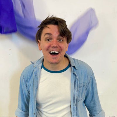 Un hombre blanco con una camiseta blanca y una chaqueta vaquera.